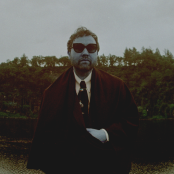 Artist Unknown Mortal Orchestra standing in front of a lake